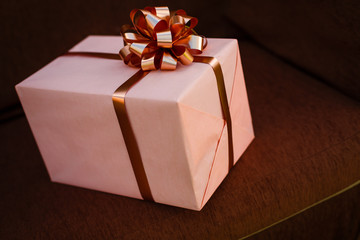 Handmade pink gift box with blue ribbon and bow on the wood old table.