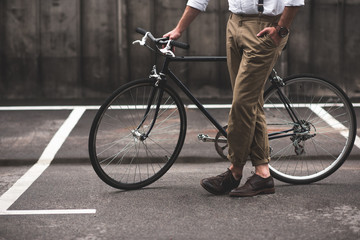 Naklejka premium low section of stylish man in brown pants standing with bicycle