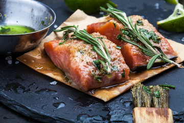 Slices of raw salmon smeared with spices and olive oil shale on a plate close-up. Preparation of fish. Salmon steak.