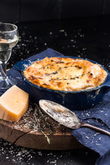 Lasagna in baking dish during eating carelessly spilled cheese, an old spoon, a glass of white...