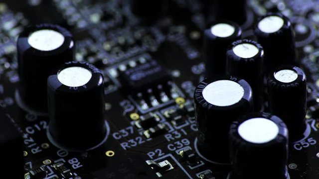 Rotating printed circuit board with microprocessors and capacitors, partially covered with electrostatic dust.