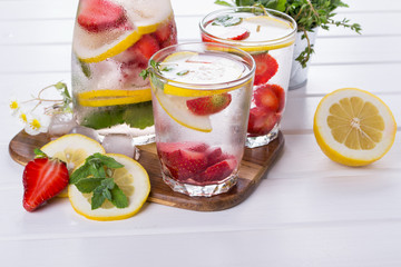 Mineral infused water with strawberry, ice, herb and mint leaves on white background, homemade detox soda water recipe.