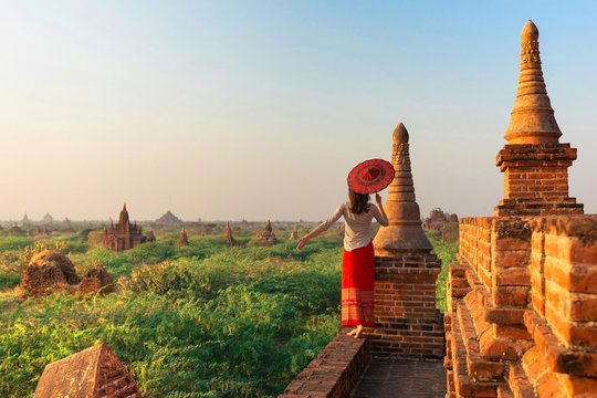 A girl with a traditional Burmese umbrella relaxing in an ancient temple during sunset, Bagan,Myanmar.Ancient temples in Bagan in sunny sunset.Young traveller enjoying a looking at Buddhist stupas.