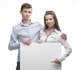 Young happy couple portrait of a confident businessman showing presentation, pointing paper placard gray background. Ideal for banners, registration forms, presentation, landings, presenting concept.