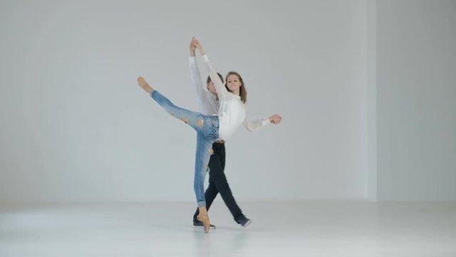 A pair of young ballet dancers performing in the white hall