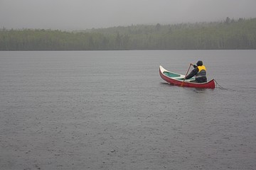 Canoeist paddling on a rainy day.