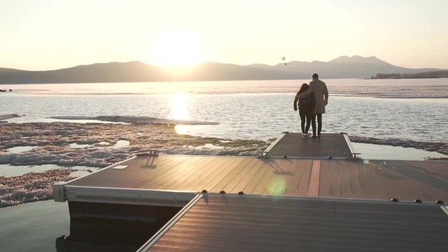 Frozen but happy couple in love walks on pier at sunset stock footage video