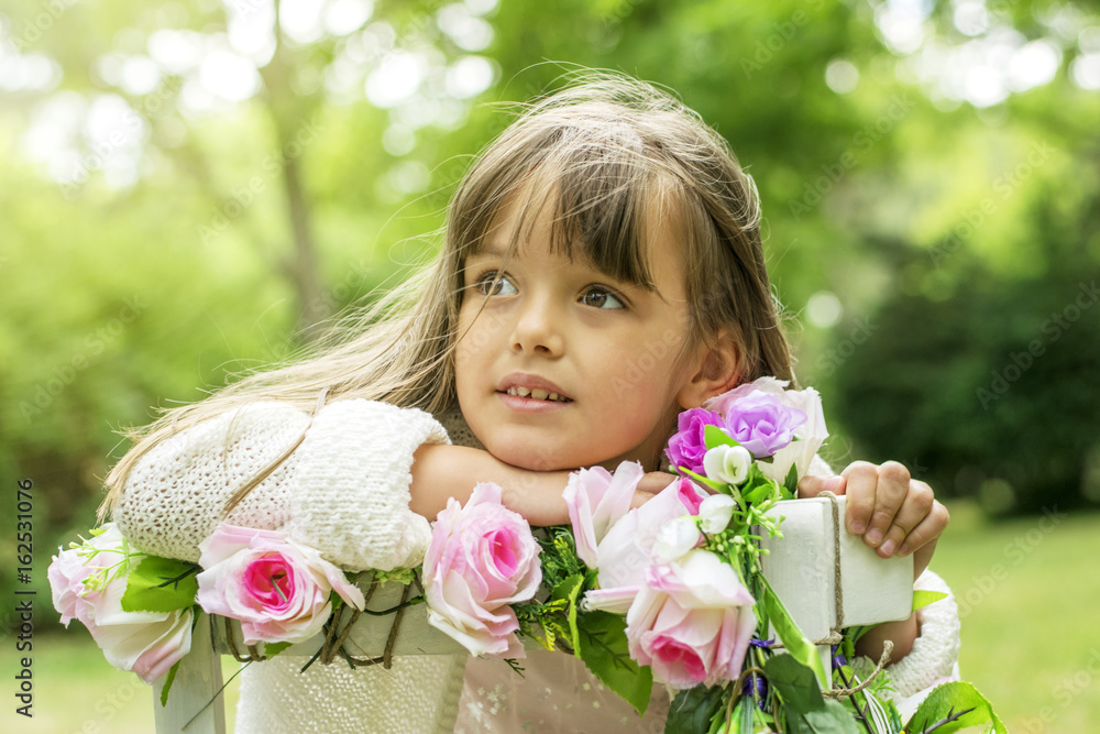 Wall mural cute kid girl posing with flowers outdoors