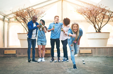 Woman playing petanque while friends drinking beer