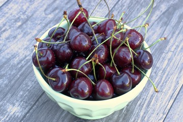 Fresh cherry in a bowl on a wooden background.