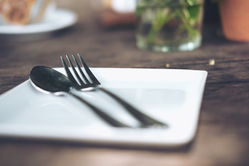 One set of spoon and fork in a white plate on vintage wooden table
