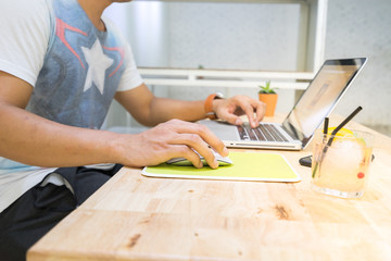 Asian man digital nomad working on a notebook computer for process clip VDO and design  logo and update promotion for his friend in facebook in cafe shop