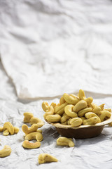 A brown wooden bowl is filled with cashew nut and it is a potrait picture shot on white background.