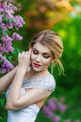 Fototapeta premium Elegant fashion model in a long white dress posing in the park