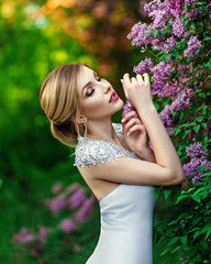 Elegant fashion model in a long white dress posing in the park