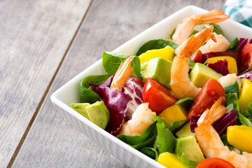 Shrimps salad with mango and avocado on wooden table
