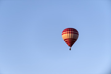 ein heißluftballon in rot und gelb vor blauem Himmel