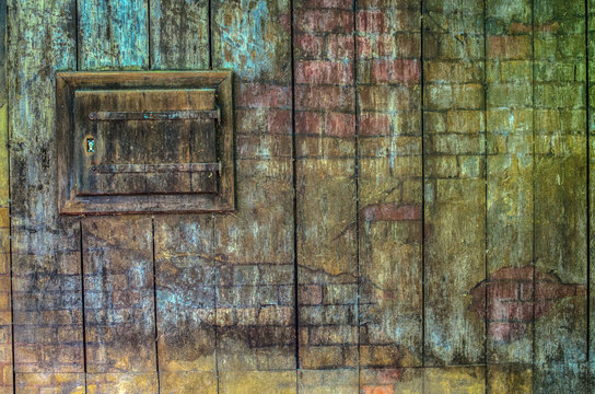 Old wooden wall background. Vintage colorful wooden wall of an old house with a small closed window.