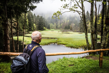 Mann macht Pause beim wandern an einem See im Wald