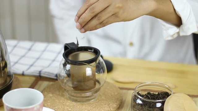 Put tea leaves and pouring water into tea leaves in glass teapot.
