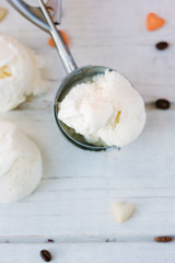 White wooden board with ice cream scoop and balls of white ice cream on it.