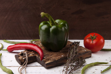 Green bell pepper on wooden cutting plank.