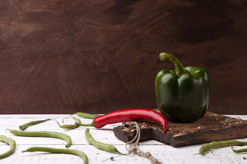 Green bell pepper on wooden cutting plank.