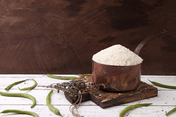 Rice in iron stewpan with green beans on wooden cutting plank. Copy cpace for text
