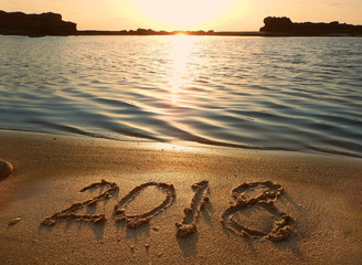inscription 2018 on the wet sand of the sea, beach in a quiet cove of the Mediterranean Sea at  the sunset