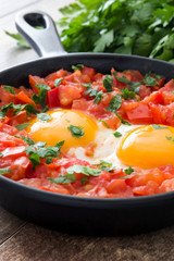Shakshuka in iron frying pan on wooden table. Typical food in Israel.
