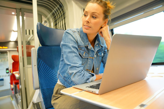 Young woman in train connected on laptop computer