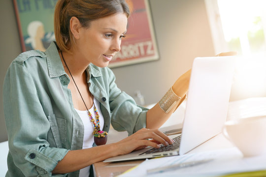 Young trendy woman at home working on laptop