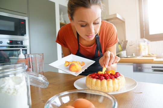 Young Woman In Modern Kitchen Baking Raspberry Cake