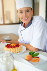Portrait of pastry chef standing by raspberry cake