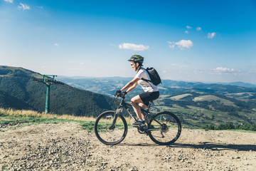 Fototapeta na wymiar Young woman riding on MTB in mountains