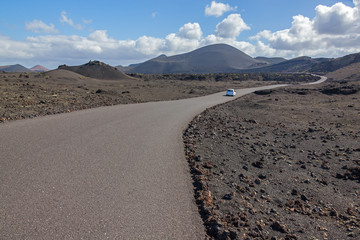 Fototapeta na wymiar Picturesque road through volcanic terrain in the Timanfaya national park on Lanzarote island, Canary Islands, Spain