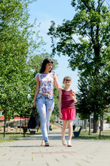 Fototapeta na wymiar mother with her 10-year-old daughter walking on a sunny day through the city