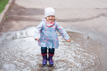 Little girl jumping in the puddle