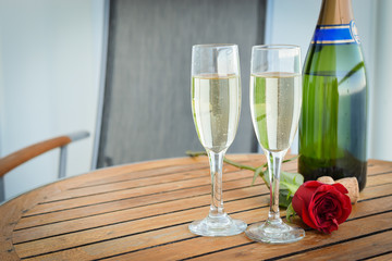 Celebration concept: Bottle of champagne, flute glasses filled with bubbles and red rose flower. © Nancy Pauwels