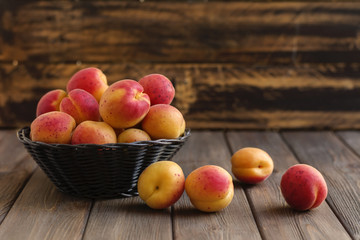 Ripe apricots in basket on wooden background