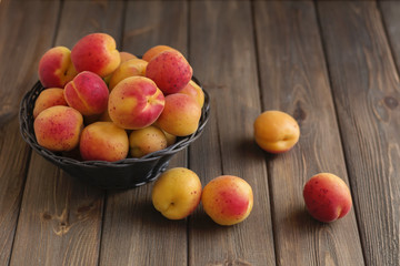 Ripe apricots in basket on wooden background