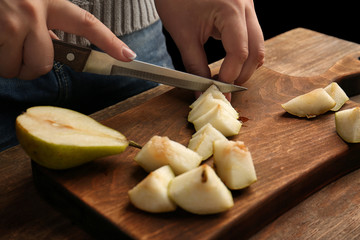 Woman slicing pear on wooden board