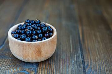 Fototapeta na wymiar Useful berry. Black currants in a wooden bowl. The concept is healthy food, vitamins, diet and vegetarianism.