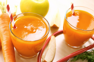 Glasses of carrot juice with fresh apple and stethoscope on the table. Health care concept