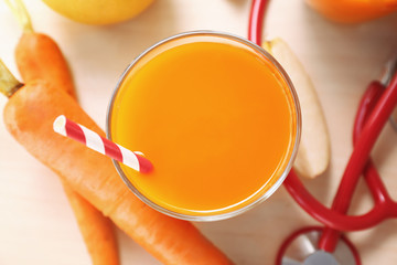 Glass of carrot juice with stethoscope on the table. Health care concept