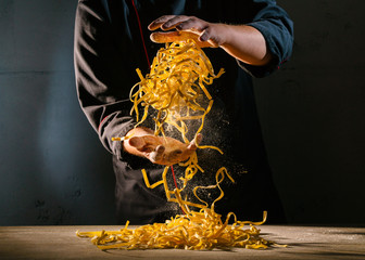 Chef adds wheat flour to the Italian ribbon-shaped pasta, before preparing the dish. Freeze motion...