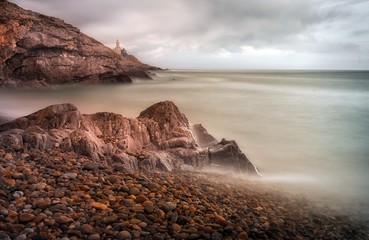 Long shutter speed calms the movement of a wave crashing on Bracelet Bay on the Gower peninsula, Swansea, South Wales.