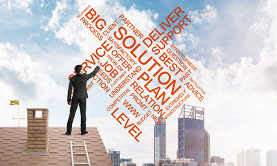 Young businessman standing on house roof and writing leadership skill concept. Mixed media