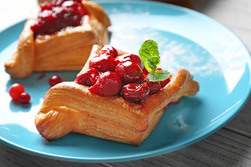 Blue plate with pastries and cherry, closeup