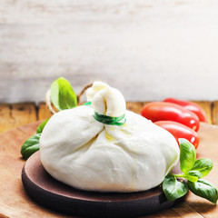 Burrata, fresh Italian cheese with red pepperoni on a wooden light background.